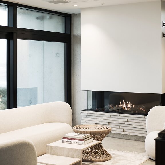 Insert à gaz VISIO 160 avec vitre sur trois côtés, mur blanc et pièce à vivre moderne