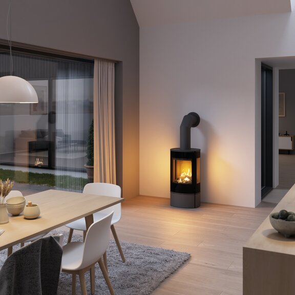Poêle à gaz CARO 90 en platine avec porte de foyer plein verre et vitres latérales dans la salle à manger avec îlot de cuisson