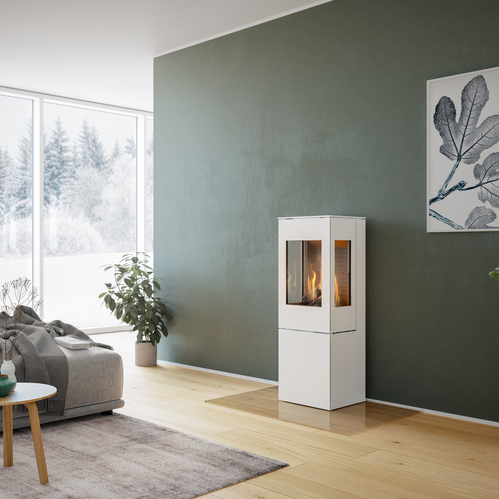NEXO 120 GAZ en blanc avec porte en acier Poêle à gaz NEXO 120 en blanc avec porte en acier et deux vitres latérales devant un mur vert dans un salon décoratif