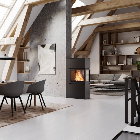 Le poêle 600 RD de couleur noire fait office de séparateur de pièce entre la salle à manger et le salon moderne.
