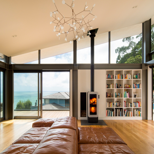 bionic fire EVO en noir avec porte de foyer plein verre blanc Poêle à bois bionic fire EVO de couleur noire avec porte de foyer plein verre blanc dans un salon au bord de la mer