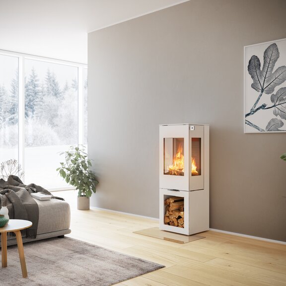 Poêle à bois NEXO 120 en blanc avec porte en acier et deux vitres latérales avec compartiment à bois dans un salon décoratif