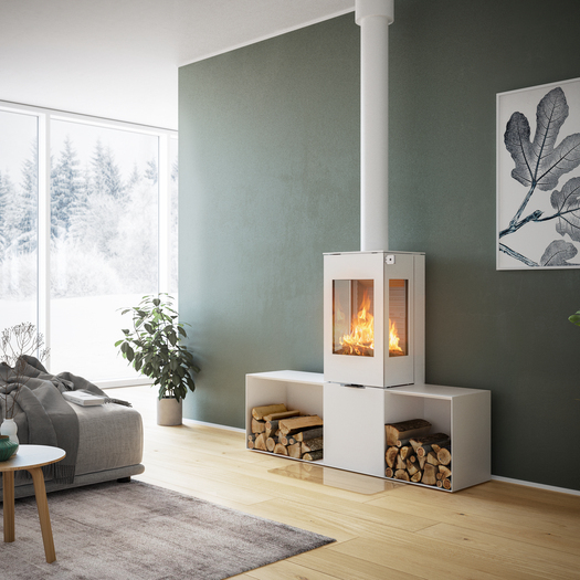 NEXO 120 en blanc avec porte en acier Poêle à bois NEXO 120 en blanc avec porte en acier, deux vitres latérales et deux bancs devant un mur vert dans un salon décoratif